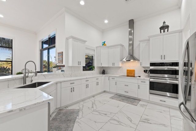 kitchen with white cabinetry, sink, wall chimney range hood, and decorative backsplash