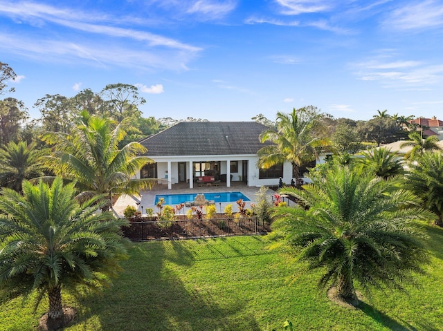 back of house with a fenced in pool, a patio area, and a lawn