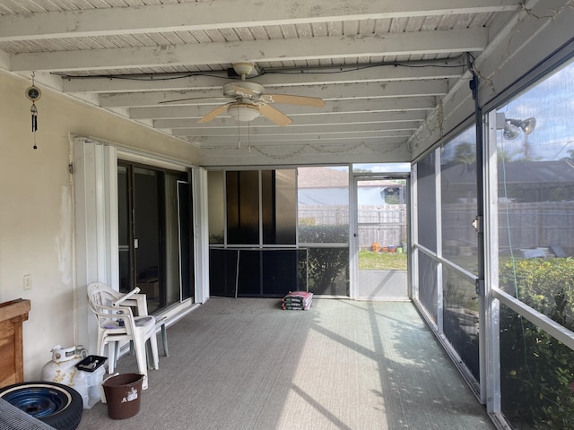 unfurnished sunroom featuring ceiling fan and beamed ceiling