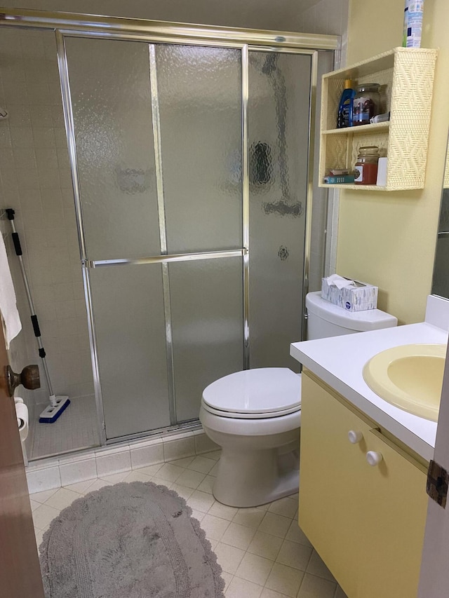 bathroom with toilet, tile patterned floors, vanity, and a shower with shower door