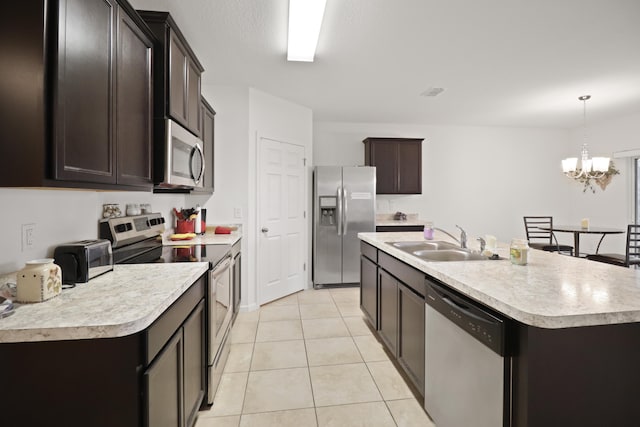 kitchen with pendant lighting, sink, light tile patterned floors, appliances with stainless steel finishes, and a center island with sink