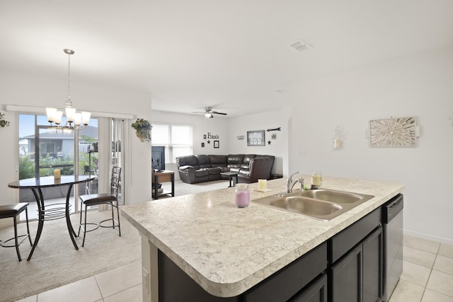 kitchen with light tile patterned flooring, decorative light fixtures, dishwasher, sink, and a center island with sink