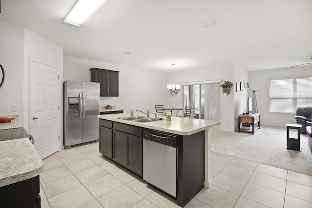 kitchen with sink, stainless steel appliances, dark brown cabinetry, a center island with sink, and light carpet