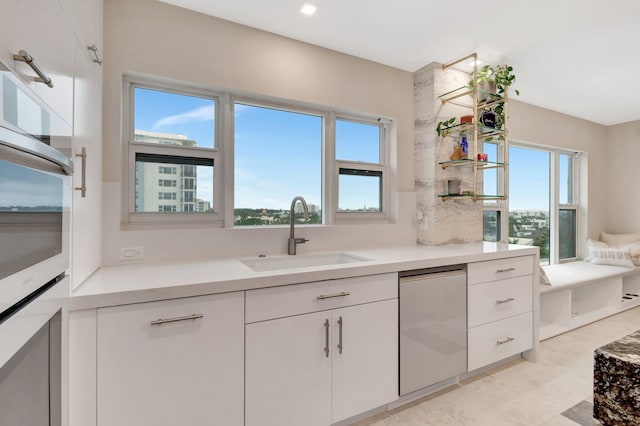 kitchen featuring white cabinets, a healthy amount of sunlight, white oven, and sink