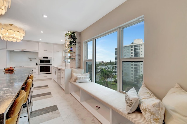 interior space with sink, white cabinetry, and white double oven