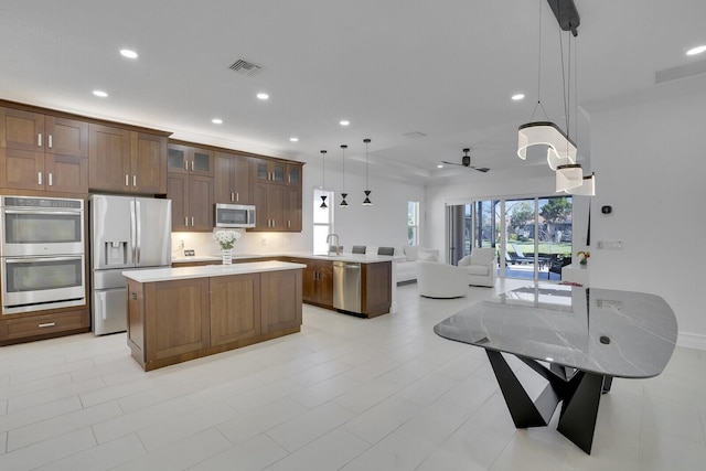 kitchen with visible vents, a kitchen island, open floor plan, light countertops, and appliances with stainless steel finishes