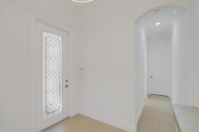 foyer with arched walkways, light tile patterned floors, and baseboards