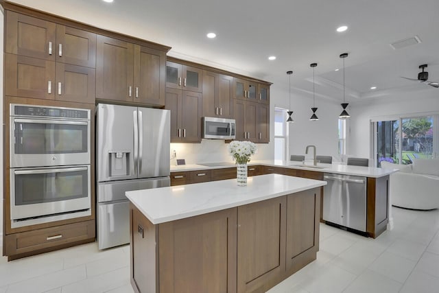 kitchen featuring a peninsula, a sink, stainless steel appliances, glass insert cabinets, and open floor plan