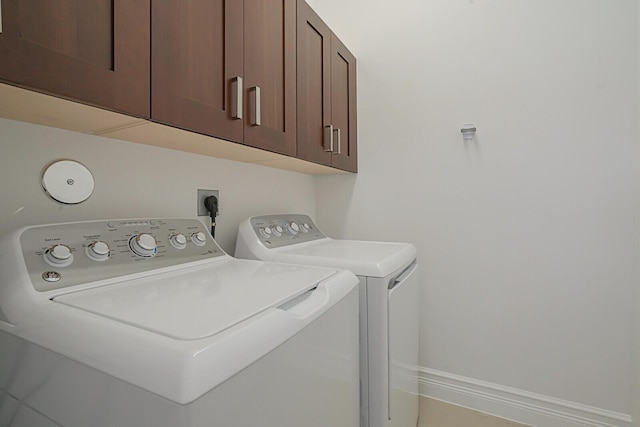 clothes washing area with cabinet space, baseboards, and separate washer and dryer