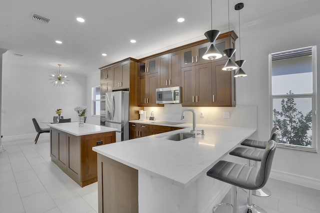 kitchen with visible vents, a center island, light countertops, stainless steel appliances, and a sink