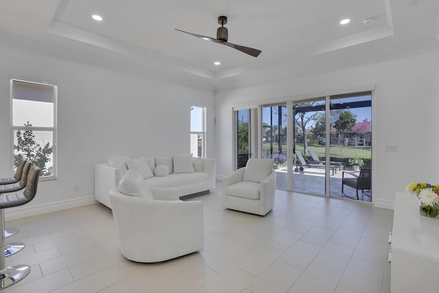 living room with a tray ceiling, baseboards, and a ceiling fan