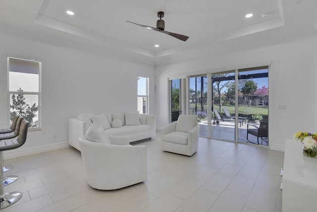 living area with recessed lighting, ceiling fan, baseboards, and a raised ceiling