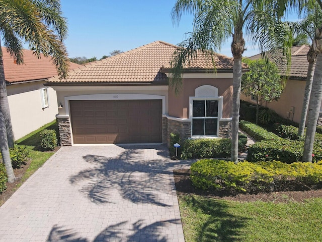 mediterranean / spanish-style house featuring decorative driveway, stone siding, a garage, and stucco siding