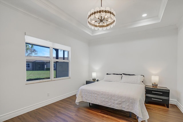 bedroom featuring wood finished floors, baseboards, crown molding, a raised ceiling, and a notable chandelier