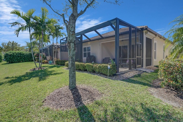 back of house with a lanai, a lawn, and stucco siding