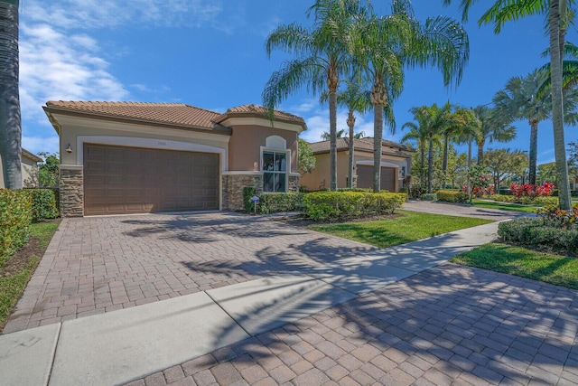 mediterranean / spanish-style home with decorative driveway, stone siding, and an attached garage