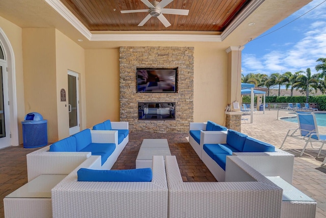 view of patio with an outdoor living space with a fireplace, a community pool, and a ceiling fan