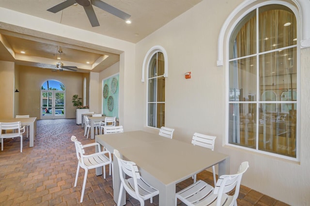 interior space with recessed lighting, a raised ceiling, brick floor, and ceiling fan