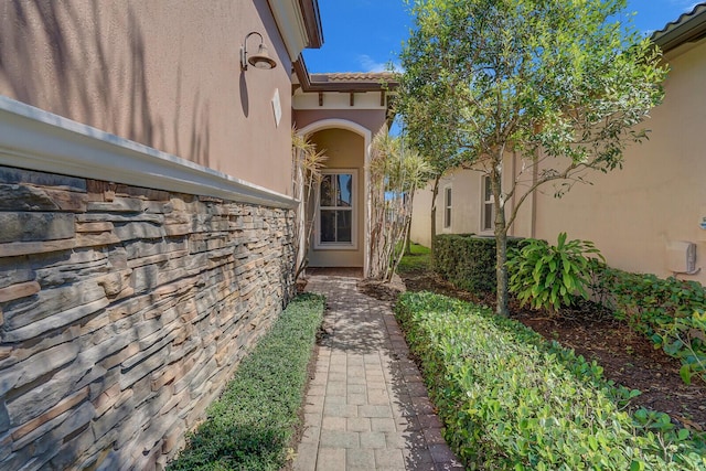 doorway to property featuring a tile roof, stone siding, and stucco siding