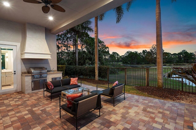 patio terrace at dusk with ceiling fan, area for grilling, outdoor lounge area, and sink