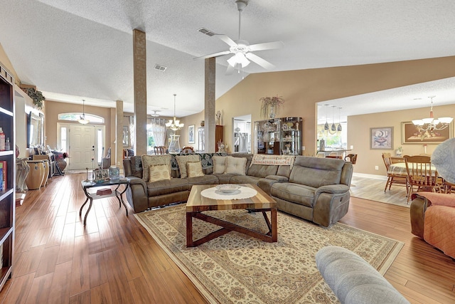 living room featuring ceiling fan with notable chandelier, wood-type flooring, lofted ceiling, and a textured ceiling