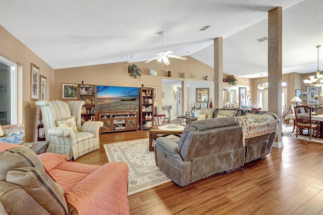 living room featuring light hardwood / wood-style floors, ceiling fan with notable chandelier, a textured ceiling, and vaulted ceiling