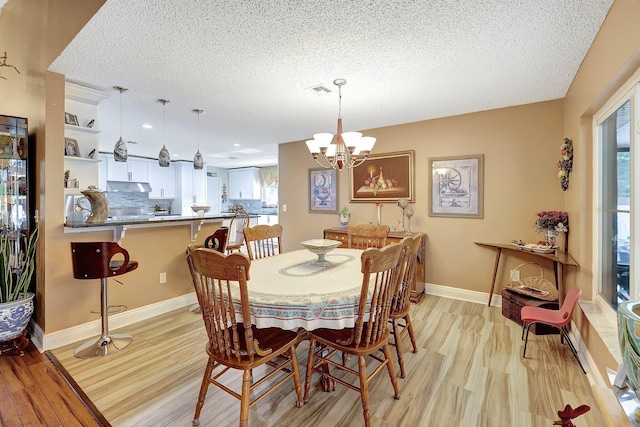 dining area featuring an inviting chandelier, a textured ceiling, and light hardwood / wood-style floors