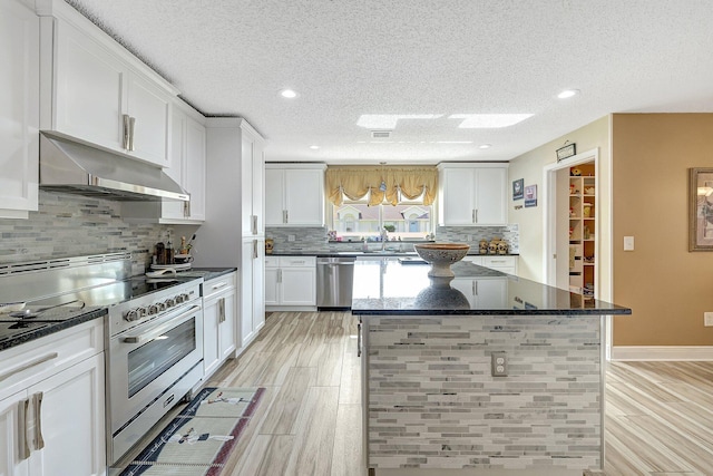 kitchen featuring white cabinetry, appliances with stainless steel finishes, a center island, and dark stone countertops