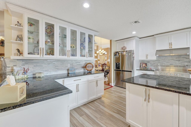 kitchen featuring decorative backsplash, white cabinetry, stainless steel fridge with ice dispenser, a textured ceiling, and dark stone counters