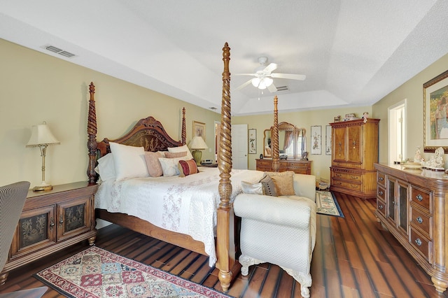 bedroom with ceiling fan, dark hardwood / wood-style floors, and a tray ceiling