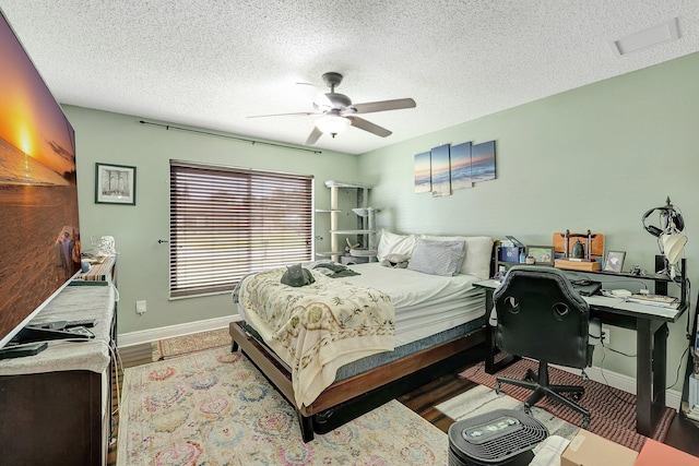 bedroom with ceiling fan, wood-type flooring, and a textured ceiling