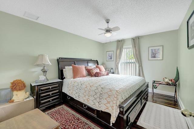 bedroom with a textured ceiling, ceiling fan, and dark hardwood / wood-style flooring