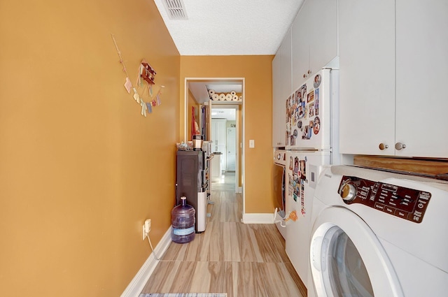 laundry area featuring a textured ceiling, cabinets, and washer / clothes dryer