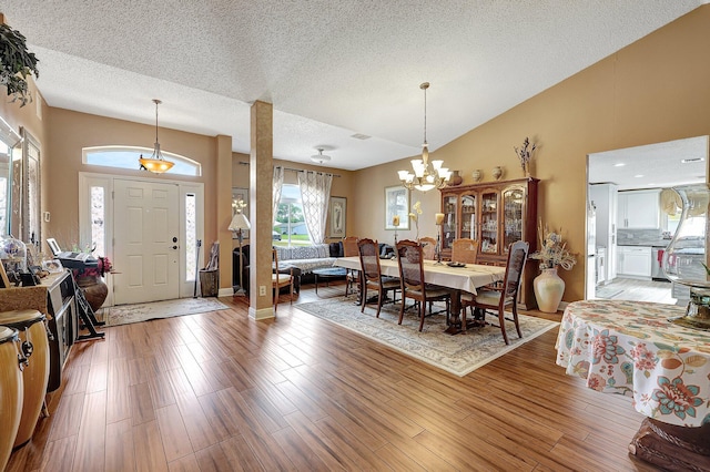 dining area featuring a textured ceiling, an inviting chandelier, lofted ceiling, and hardwood / wood-style flooring