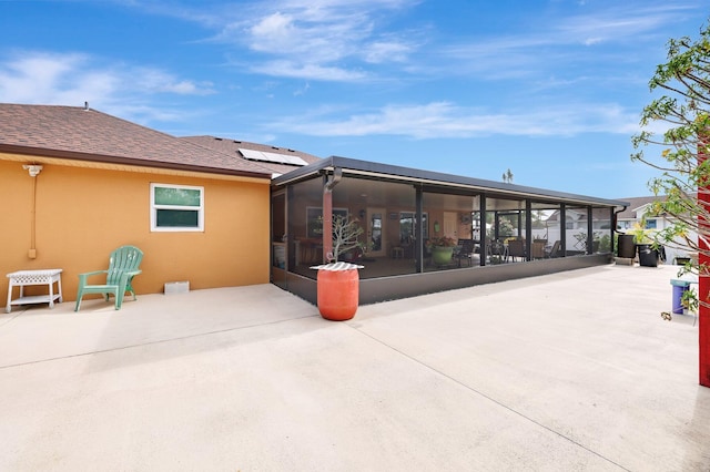 rear view of property featuring a sunroom, solar panels, and a patio