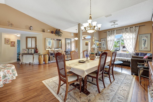 dining room with vaulted ceiling, an inviting chandelier, a textured ceiling, and hardwood / wood-style floors