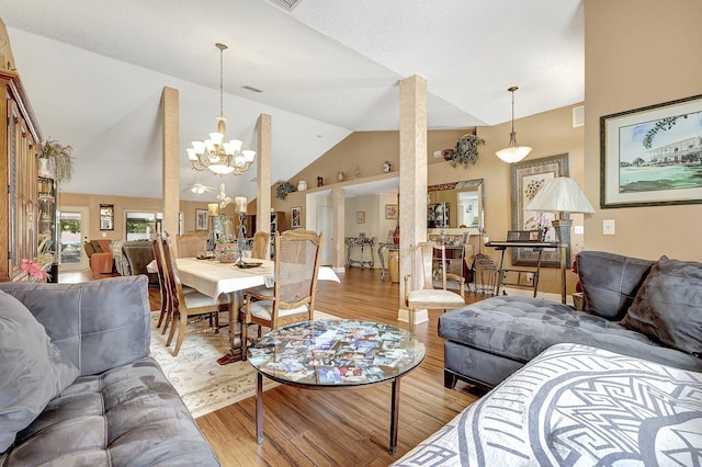 living room with light wood-type flooring, an inviting chandelier, and vaulted ceiling