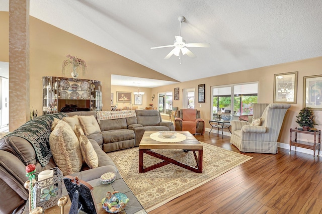 living room with lofted ceiling, ceiling fan with notable chandelier, a textured ceiling, and hardwood / wood-style floors