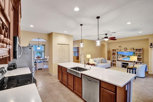 kitchen with ceiling fan, a center island with sink, sink, hanging light fixtures, and stainless steel appliances