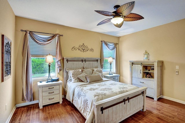 bedroom with ceiling fan, multiple windows, and dark hardwood / wood-style floors