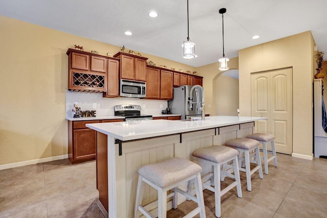 kitchen featuring a breakfast bar, sink, hanging light fixtures, appliances with stainless steel finishes, and an island with sink