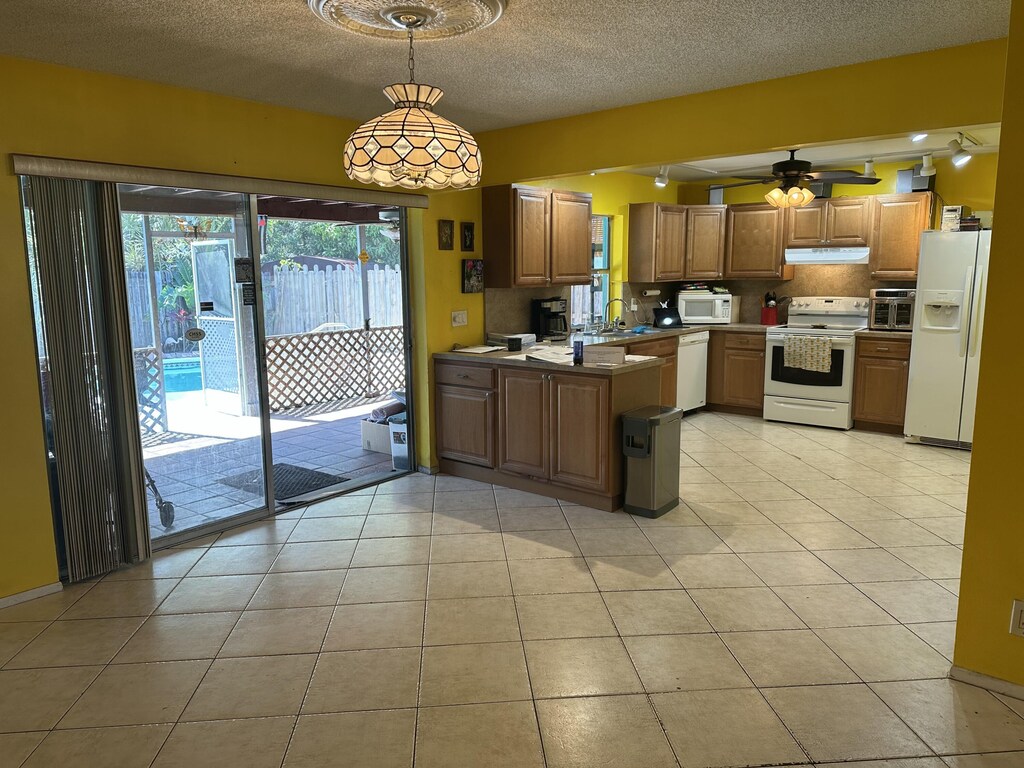 kitchen with ceiling fan, backsplash, sink, light tile patterned flooring, and white appliances