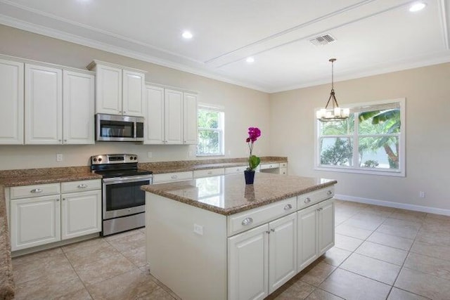 kitchen with pendant lighting, white cabinets, appliances with stainless steel finishes, a center island, and light stone counters