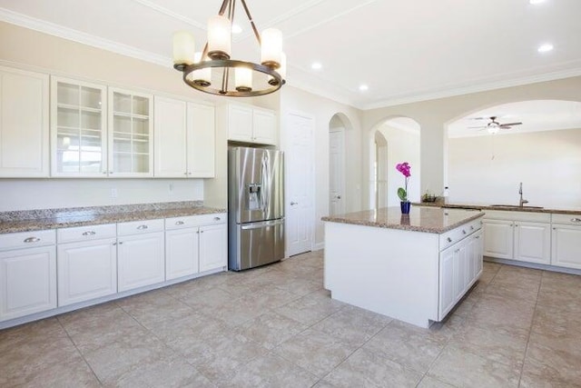 kitchen featuring stainless steel refrigerator with ice dispenser, pendant lighting, white cabinets, light stone countertops, and a center island