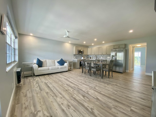 living room featuring ceiling fan, heating unit, and light hardwood / wood-style flooring