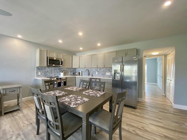 kitchen featuring sink, backsplash, appliances with stainless steel finishes, and light wood-type flooring