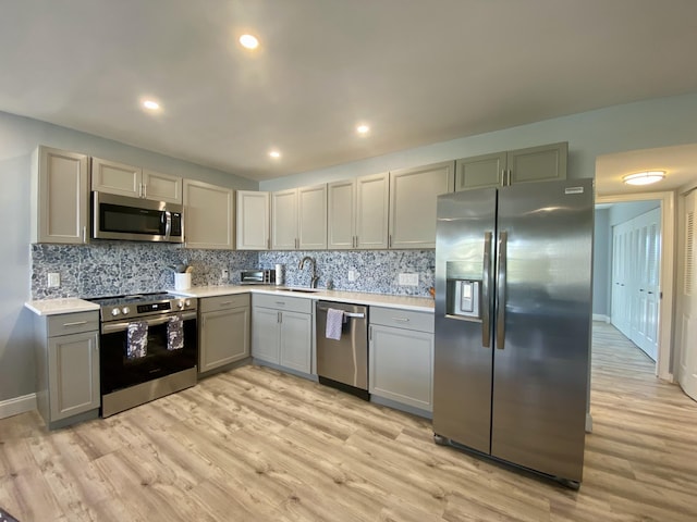 kitchen with light wood-type flooring, gray cabinets, stainless steel appliances, and sink