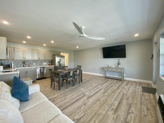 living room with ceiling fan, light hardwood / wood-style flooring, and sink