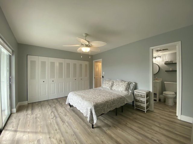 bedroom with light wood-type flooring, ceiling fan, and ensuite bath