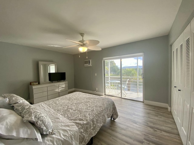 bedroom with light hardwood / wood-style floors, a closet, a wall unit AC, access to outside, and ceiling fan